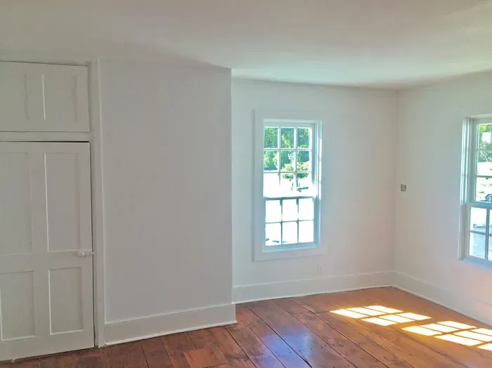 Habitación con paredes blancas recién pintadas y suelo de madera