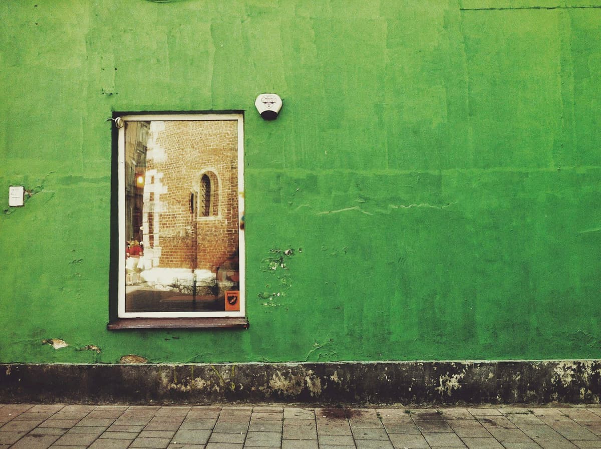 a green building with a window and a clock